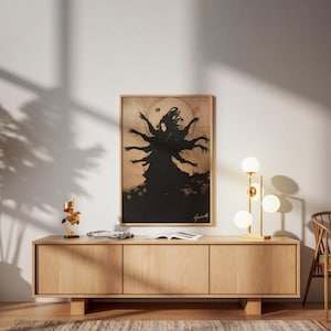 May include: A framed artwork featuring a black silhouette of a multi-armed figure against a tan background. The artwork is displayed above a light wood cabinet with a gold lamp and decorative sculpture.