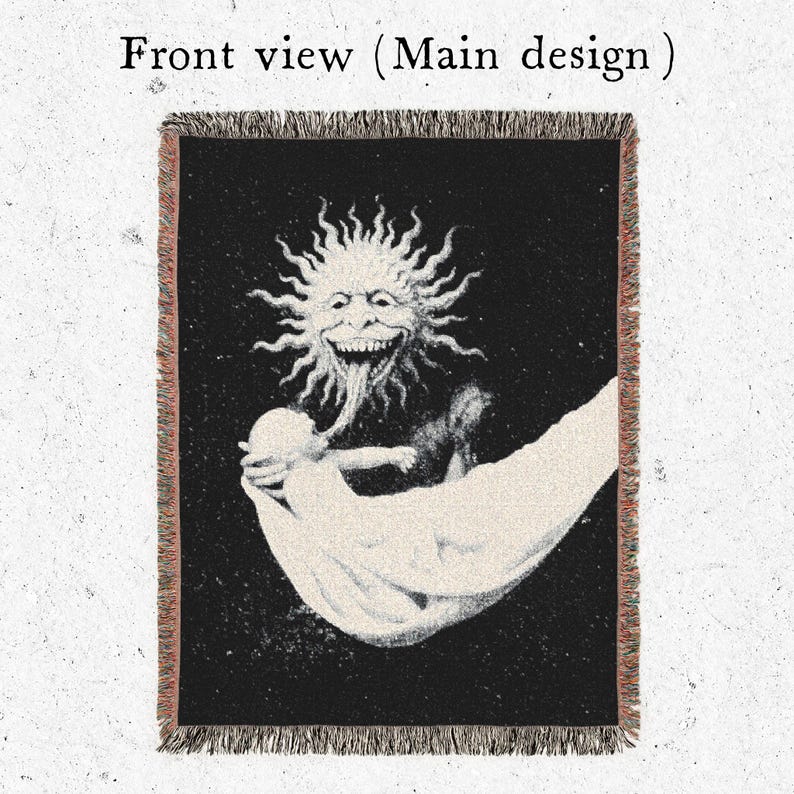 Puede incluir: Manta negra con una ilustraci&oacute;n detallada de una figura solar con una larga lengua, sosteniendo una figura en un pa&ntilde;o blanco. El texto "Front view (Main design)" est&aacute; en la parte superior. La manta tiene un borde con flecos.