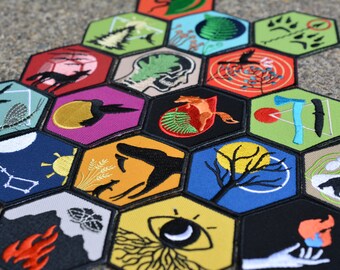 Puede incluir: Un conjunto de 18 parches bordados hexagonales con varios diseños inspirados en la naturaleza, que incluyen un zorro, un oso, un pájaro, un árbol, una mano y una luna. Los parches están dispuestos en un patrón de panal y tienen un contorno negro.