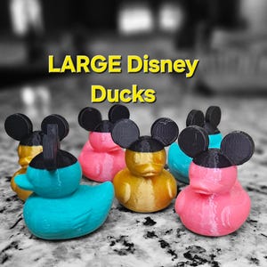 May include: Four large rubber duck toys with Mickey Mouse ears. The ducks are painted in blue, pink, gold, and light pink.