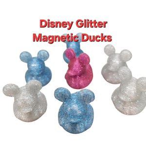 May include: Six glitter duck figurines with magnetic backs. The ducks are in blue, pink, and white.
