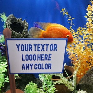 May include: A blue and white sign with the text "YOUR TEXT OR LOGO HERE ANY COLOR" in a blue font. The sign is in front of a fish tank with a bright orange fish and green plants.