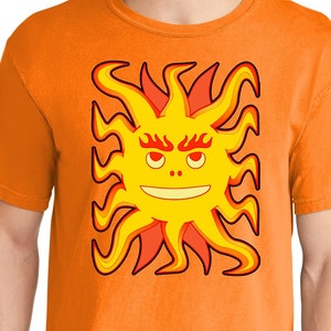 May include: Orange t-shirt with a cartoon sun with a smiling face and red and yellow flames.