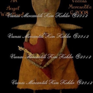 Könnte beinhalten: Eine handgemachte Stoffpuppe, die ein Herz in ihren Händen hält. Die Puppe trägt ein gelbes und braunes gestreiftes Kleid. Das Gesicht der Puppe ist mit braunen Augen und einem roten Mund bemalt. Die Puppe hält ein rotes Herz mit goldenen Verzierungen. Die Puppe ist mit "Folk Art Angel With Heart" betitelt und mit "Veenas Mercantile Kim Kohler ©2012" signiert.