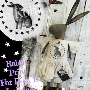 May include: A handmade rag doll bunny with a white dress and a black and white rabbit print on the front. The doll has a brown face and long ears. The doll is standing on a wooden base. The text "Audry Kim Kohler 2015" is printed on the base. The text "Rabbit Print For Body Is Included" is printed on a black background with white stars.