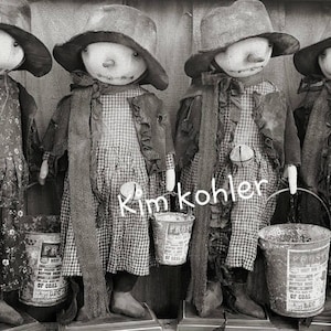 May include: Four black and white rag dolls wearing hats and holding small buckets. The dolls are dressed in vintage-style clothing with floral and plaid patterns. The dolls are standing on a wooden surface.