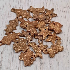 May include: A collection of 15 gold-toned metal charms in the shape of leaves. The charms have a textured surface and are perfect for adding a touch of elegance to jewelry or crafts.