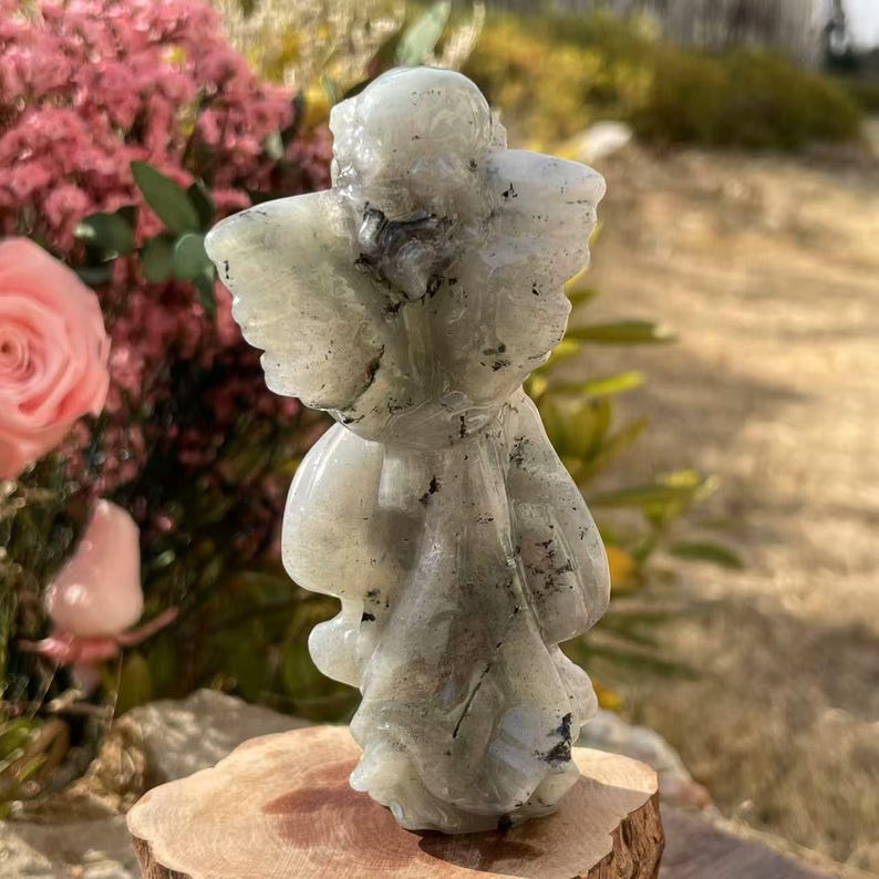 Pu&ograve; includere: Una statuetta di angelo intagliata in labradorite verde con un bagliore iridescente. L'angelo &egrave; in piedi con le ali spiegate e ha un aspetto delicato ed etereo.