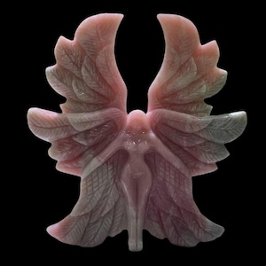 Puede incluir: Un ángel tallado en piedra preciosa rosa y verde con las alas extendidas. El ángel está tallado en un estilo detallado e intrincado.