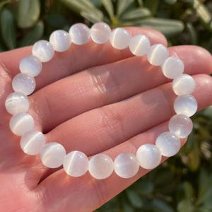 May include: White gemstone bracelet with round beads. The beads have a shimmery, iridescent finish.