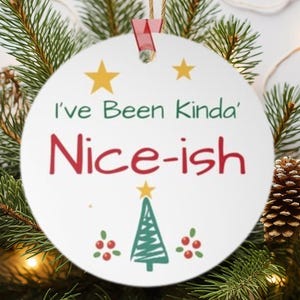 May include: White round Christmas bauble with green and red accents. It features a stylised Christmas tree with a star on top and the text "I've Been Kinda' Nice-ish".