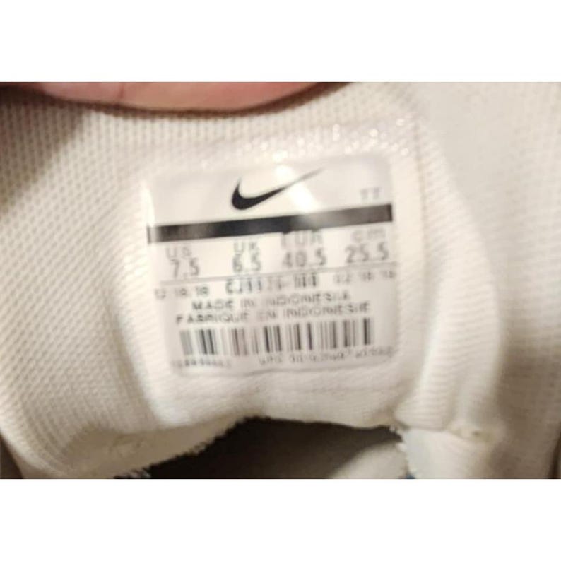 Puede incluir: Primer plano del interior de un zapato blanco con el logotipo de Nike e informaci&oacute;n de tallas. La etiqueta indica la talla US 7.5, UK 6.5, EUR 40.5 y 25,5 cm. Fabricado en Indonesia.