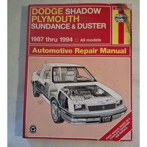May include: A Haynes automotive repair manual for Dodge Shadow, Plymouth Sundance & Duster models from 1987 to 1994. The cover is red with white text and a detailed illustration of a car. The manual includes the text "Automotive Repair Manual".
