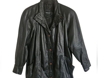 May include: A black leather jacket with a button closure and two pockets. The jacket has a collar and long sleeves. The label on the jacket reads "Pelle."