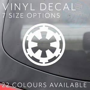 May include: White vinyl decal featuring the Galactic Empire symbol. The decal is circular with a stylized, symmetrical design. Text at the top reads "VINYL DECAL" and "7 SIZE OPTIONS." The bottom text says "22 COLOURS AVAILABLE."