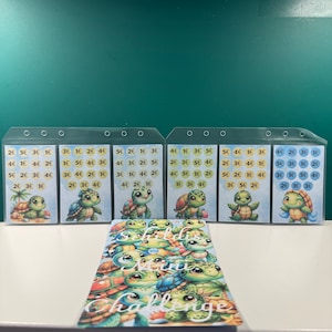 Könnte beinhalten: Sechs transparente Plastikkarten mit bunten Schildkrötenillustrationen und darauf gedruckten Zahlen. Die Karten sind mit verschiedenen Stückelungen beschriftet, darunter 1, 2, 3, 4 und 5. Unter den Karten befindet sich eine bunte Karte mit einer Schildkrötenillustration und dem Text "Turtle Mini Challenge".