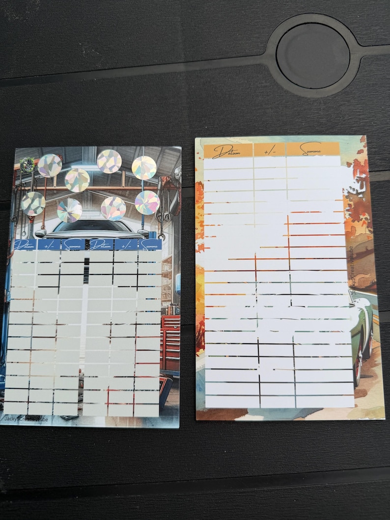 May include: Two rectangular paper tracking sheets with grid lines for recording data. The left sheet features a garage scene with holographic circles at the top. The right sheet displays an autumn road scene with a car. Both include the text Datum, +/-, Summe.