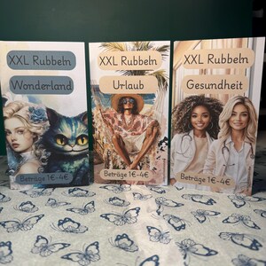 Könnte beinhalten: Drei Karten mit dem Text "XXL Rubbeln". Die Karten zeigen Bilder einer Frau und einer Katze, einer Person mit Sonnenbrille und zwei Frauen in weißen Kitteln. Die Karten liegen auf einer Oberfläche mit Schmetterlingsmuster. Der Text "Beträge 1€-4€" ist sichtbar.