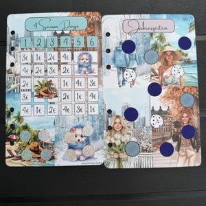 May include: Two rectangular planner inserts with punched holes on the left side. The left insert is titled 4 Season Dingo with a grid of numbers and currency values. The right insert is titled Jahreszeiten and features seasonal imagery with dark blue circles.