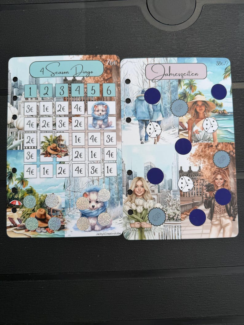 May include: Two rectangular planner inserts with punched holes on the left side. The left insert is titled 4 Season Dingo with a grid of numbers and currency values. The right insert is titled Jahreszeiten and features seasonal imagery with dark blue circles.