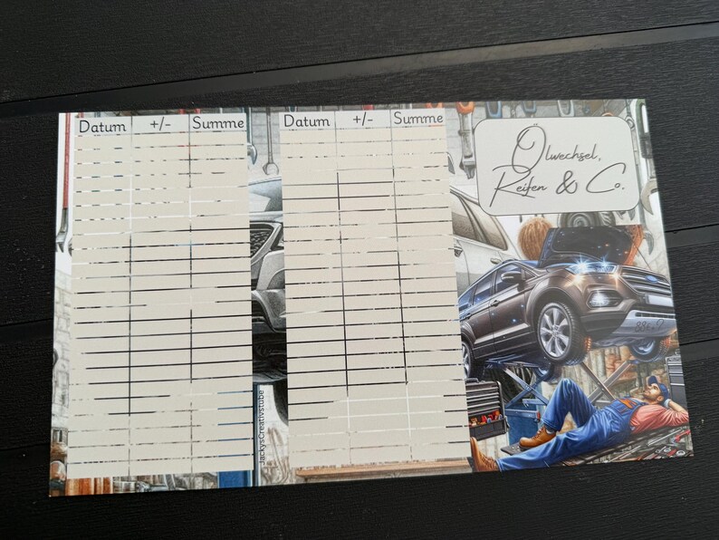 May include: A rectangular paper log sheet featuring two columns for tracking dates, plus-minus values, and totals. The design includes a graphic of a mechanic working under a car on a lift, with the text "&Ouml;lwechsel, Reifen & Co." in a white box.
