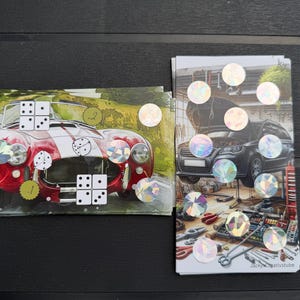 May include: Two rectangular cards featuring automotive imagery. The left card shows a red sports car with white stripes and dice graphics. The right card depicts a black car in a garage with tools and holographic circular stickers throughout both.