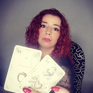 Psychic reader holding Lenormand cards featuring symbols such as the Ring and the Heart, representing love, commitment, and emotional guidance. This image illustrates a professional lenormand cards reading and psychic reading session focused on relationships, clarity, and intuitive insights, offering accurate future reading through traditional Lenormand divination cards.