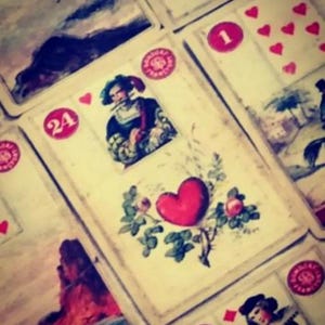 Close-up of vintage oracle and tarot-style cards featuring a red heart symbol, representing a love psychic reading. This image reflects an intuitive love reading focused on emotions, relationships, and romantic connections, offering future reading insights about love, commitment, reconciliation, and emotional destiny for those seeking guidance and clarity in matters of the heart.