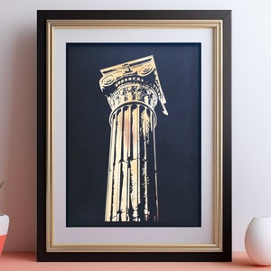 Może przedstawiać: Wydruk w ramie przedstawiający złoconą kolumnę na ciemnoniebieskim tle. Kolumna jest klasycznym elementem architektonicznym z bogato zdobioną głowicą.