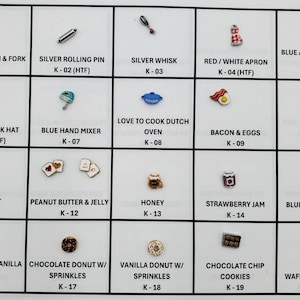 Könnte beinhalten: Eine Sammlung von Miniatur-Anhängern zum Thema Essen und Küche. Enthält einen silbernen Löffel und eine Gabel, eine Teigrolle, einen Schneebesen, eine rot-weiße Schürze, einen Topflappen, einen Kochhut, einen Handmixer, einen Dutch Oven, Speck und Eier, Pfannkuchen, Pop-Tarte, Erdnussbutter und Gelee, Honig, Erdbeermarmelade, Blaubeermuffin, Schoko-Vanille-Donut, Schoko-Donut mit Streuseln, Vanille-Donut mit Streuseln, Schoko-Chip-Cookies und Waffel mit Beeren.