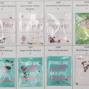 May include: A display of various craft supplies, including heart-shaped crystals, stardust mixes, and themed embellishments. The image features clear plastic bags with text like "Harry Potter" and "Wizard of Oz".