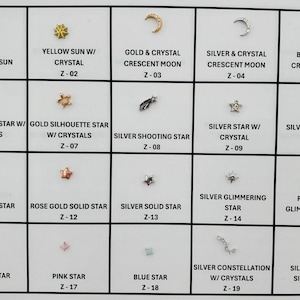 May include: A grid of small, decorative jewelry pieces, including suns, moons, stars, and constellations. The pieces are in gold, silver, rose gold, and crystal, with various designs and textures. Each piece is labeled with a name and a corresponding number.