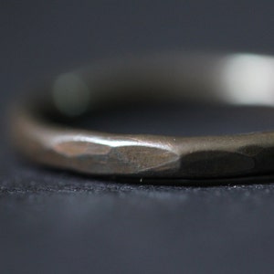 Puede incluir: Un anillo de banda de plata simple con una textura martillada.