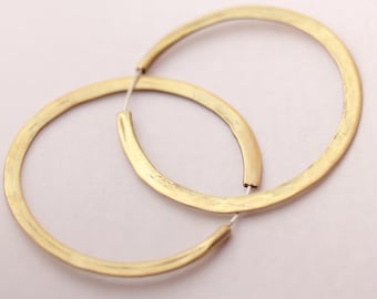 Könnte beinhalten: Ein Paar goldene Creolen. Die Creolen sind dick und haben eine gehämmerte Oberfläche.