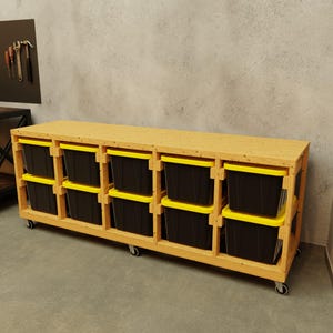 May include: A wooden storage unit with multiple compartments, each holding a black bin with a yellow lid. The unit is on wheels and has a natural wood finish. Tools hang on the wall in the background.