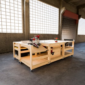May include: A wooden workbench with a mitre saw, drill, and other tools. The workbench has shelves and drawers for storage. It is on wheels and can be moved around a workshop.