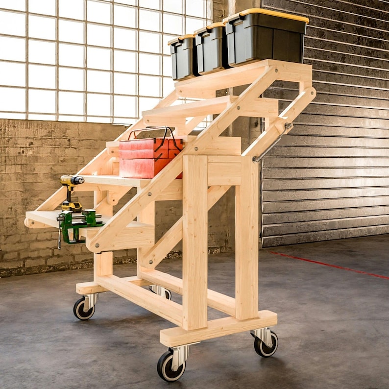 May include: A wooden rolling workbench with a fold-down top and shelves for storage. The workbench has a vise and a drill on the top shelf. There are four storage bins on the top shelf, two are yellow and two are black.