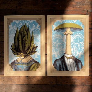 May include: Two vintage-style prints with a blue and white patterned background. The print on the left features a person with a green succulent plant for a head wearing a blue and gold dress. The print on the right features a person with a brown mushroom for a head wearing a blue suit and a white shirt with a bow tie.