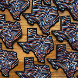 Peut inclure: Plusieurs patchs brodés colorés en forme de l'état du Texas. Chaque patch présente une grande étoile multicolore au centre.