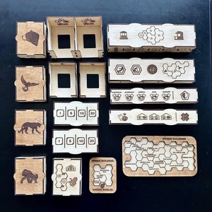 May include: Wooden game pieces for a board game. The pieces are in various shapes and sizes, and some have animal illustrations. The pieces are labeled with numbers and the words "Unique Buildings" and "Marine Worlds".