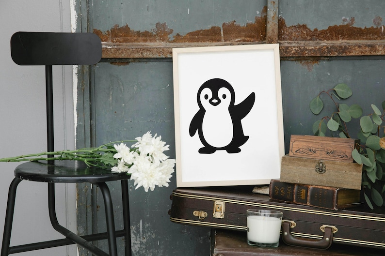 May include: A framed print featuring a black and white cartoon penguin with a raised wing. The artwork is displayed on a white background. The image is set against a rustic backdrop with a black chair, flowers, and vintage luggage.