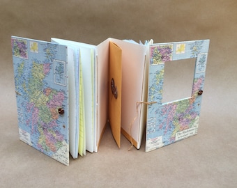May include: A handmade journal with a map of Scotland on the cover. The journal has a brown leather strap and a pocket on the inside cover. The text on the cover reads "The Blackmounts in Scotland 1964".
