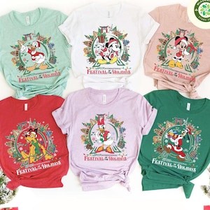 May include: A collection of six t-shirts in various colors, each featuring a Disney character in a holiday-themed design. The shirts display characters like Mickey Mouse, Donald Duck, and Goofy, with the text "EPCOT International Festival of the Holidays."