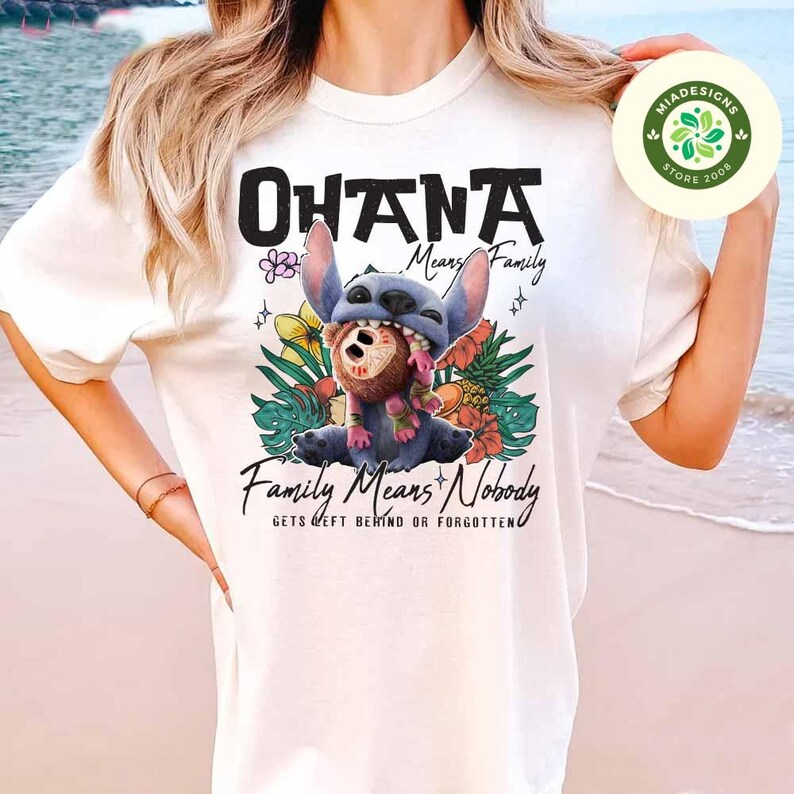 May include: White t-shirt featuring a graphic of the character Stitch from Lilo & Stitch. The design includes the word "OHANA" and the phrase "Family Means Nobody Gets Left Behind or Forgotten". The image has a tropical theme.