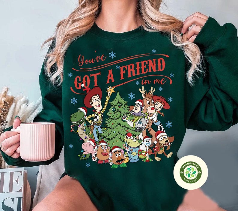 May include: Dark green sweatshirt featuring a festive design with characters from the Toy Story movie. The text "You've Got a Friend in Me" is displayed above the characters. The design includes a Christmas tree and snowflakes.