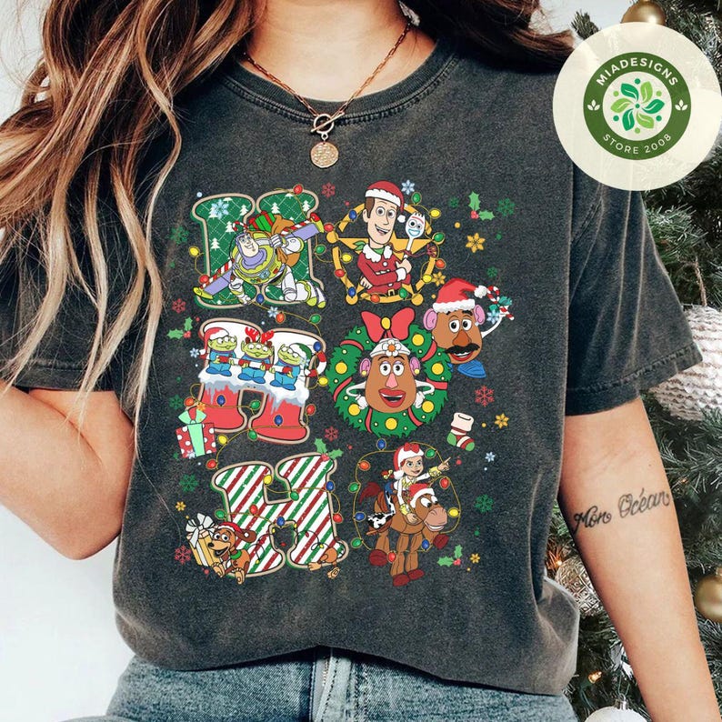 Puede incluir: Camiseta gris oscuro con un dise&ntilde;o festivo "HI" con personajes de Toy Story. El dise&ntilde;o incluye a Buzz Lightyear, Woody y otros personajes en decoraciones navide&ntilde;as. La camiseta tiene un aspecto vintage y desgastado.
