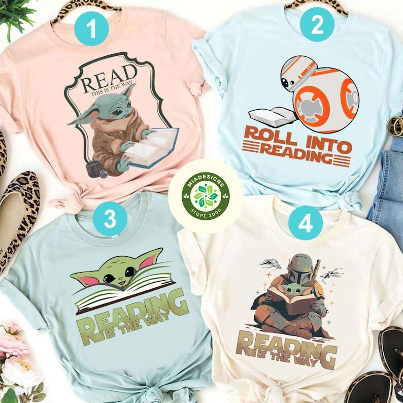 May include: Four different t-shirts featuring Star Wars characters reading books. The shirts are light pink, light blue, light blue, and cream. The text on the shirts reads "Read This is the Way", "Roll into Reading", "Reading is the Way", and "Reading is the Way".