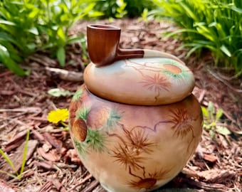 Umidificador de tabaco vintage em porcelana com um cachimbo na tampa servindo de alça.