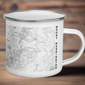 May include: White enamel camping mug with a black and white topographic map of Mount Washington, New Hampshire. The mug has a silver rim and handle. "MOUNT WASHINGTON" is printed vertically on the side of the mug.
