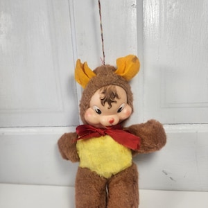 May include: A white ceramic mug with a black handle and the text "But First, Coffee" in a bold, black font. The mug is set against a blurred background, suggesting a cozy setting. The mug appears to be approximately 4 inches tall.